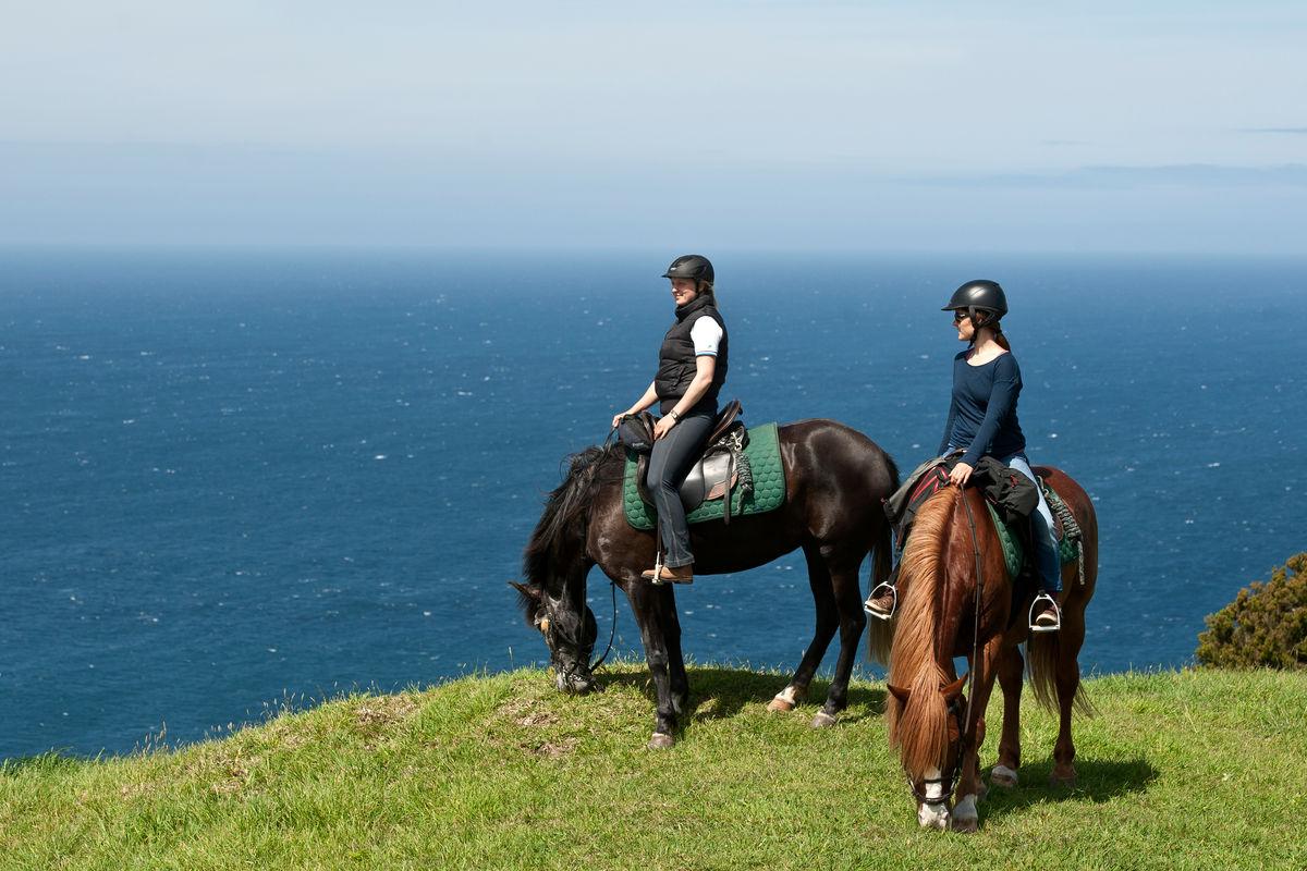 Two girls riding horses on the background of the sea